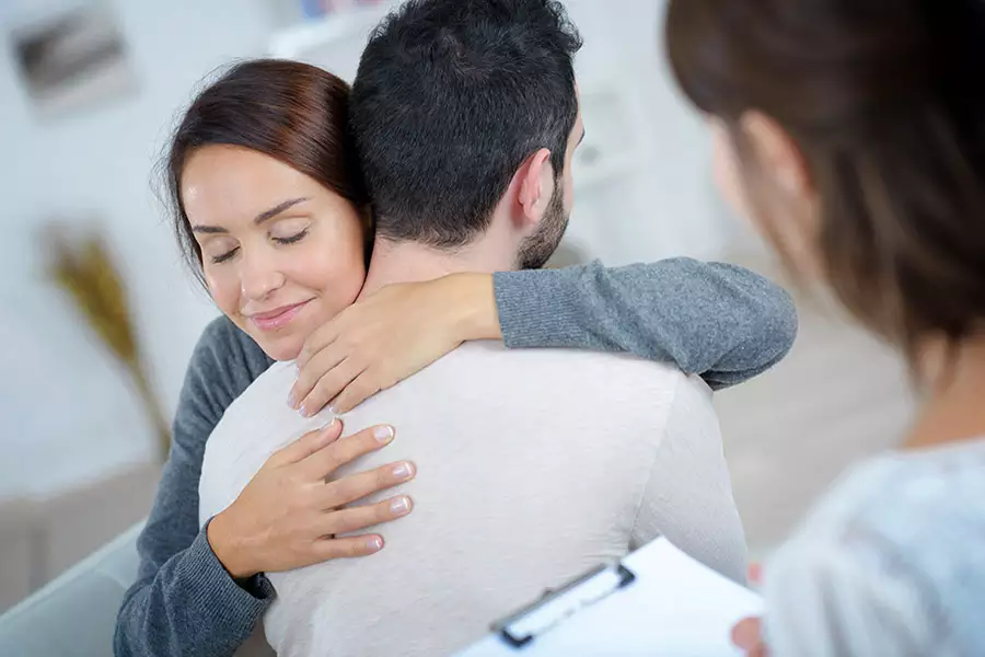 Mulher abraça um familiar durante atendimento acompanhado por uma profissional de saúde